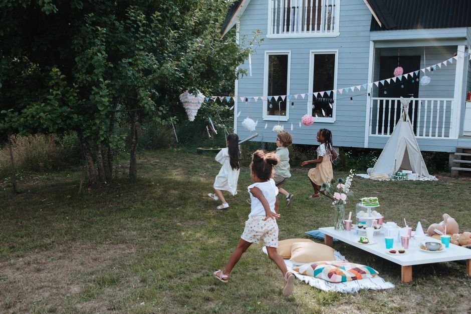 Vaikai linksmai švenčia gimtadienį lauke, puošniame kiemelyje su pinata